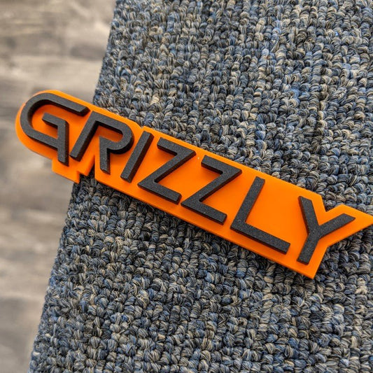 Grizzly Car Badge - Matte Black On Orange - Squid Font - Tape Mount