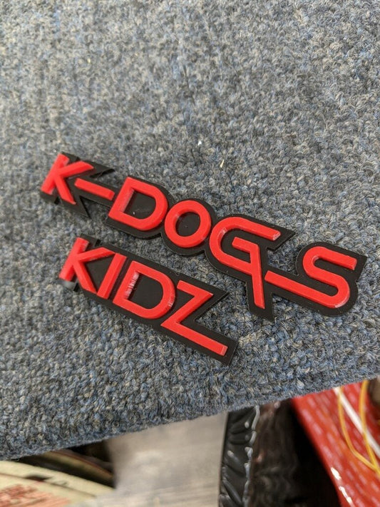 K Dogs Kidz Car Badge - Red On Matte Black - Squid Font - Tape Mount - Atomic Car Concepts