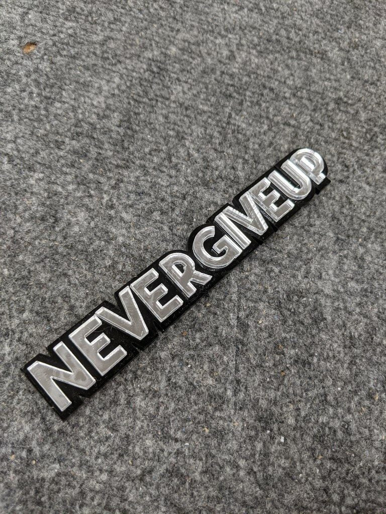 Never Give Up Car Badge - Mirror Silver On Gloss Black - Block Font - Atomic Car Concepts