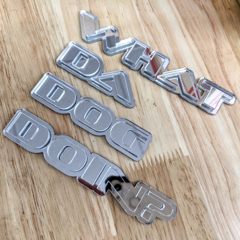 What Da Dog Doin Car Badge - Mirror Silver - OEM Font - Tape Mounting - Atomic Car Concepts